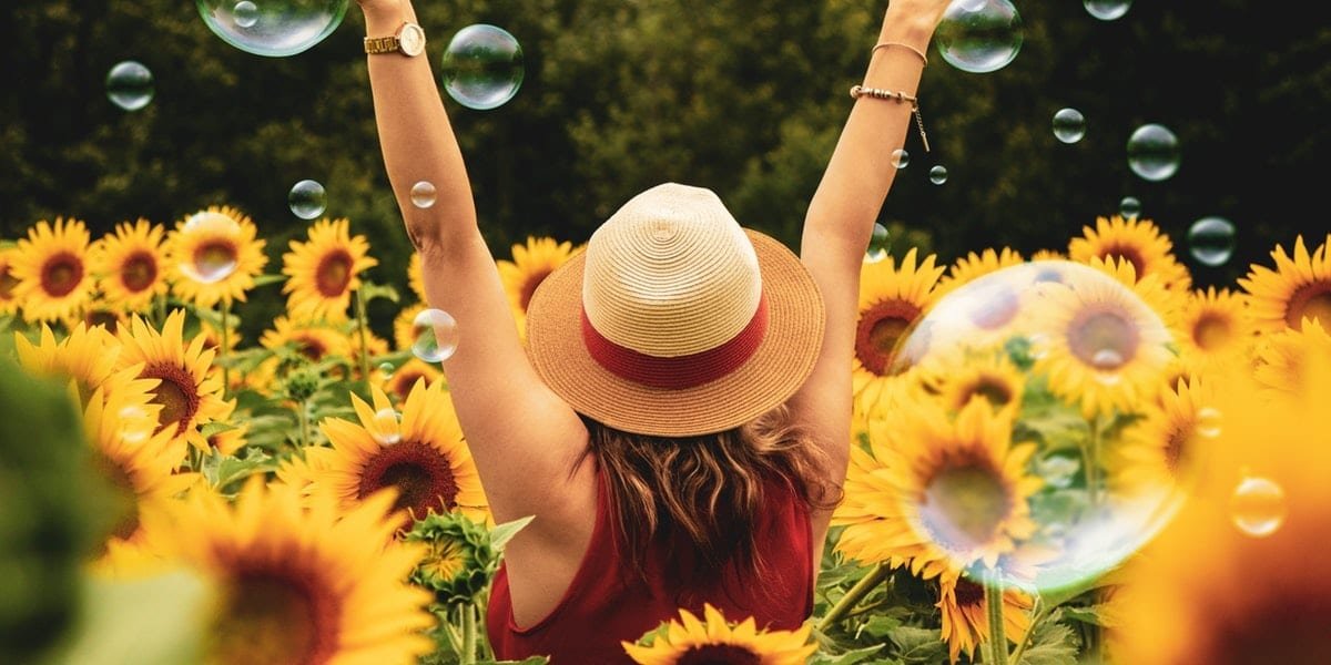 girl standing in a sunflower field with her arms up