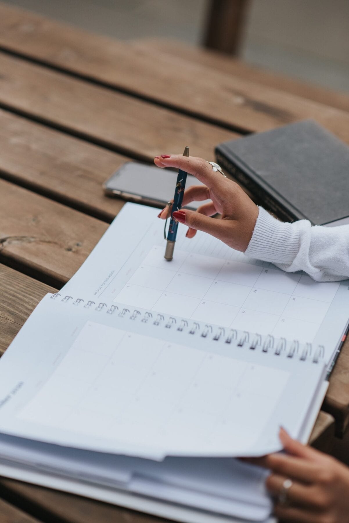 Crop ethnic businesswoman with open notepad at table