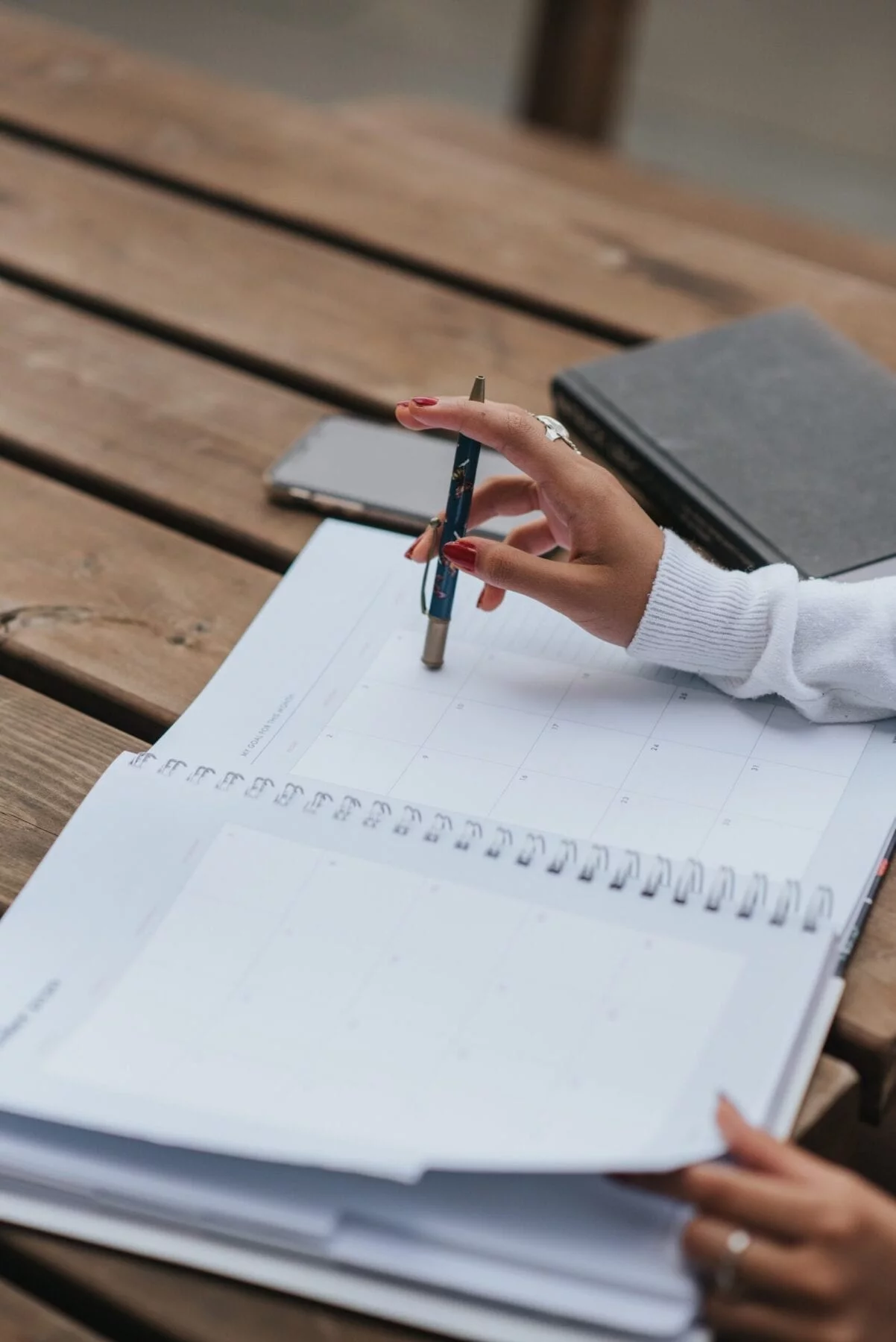 a woman using a manifestation journal Crop ethnic businesswoman with open notepad at table; a woman using a manifestation journal