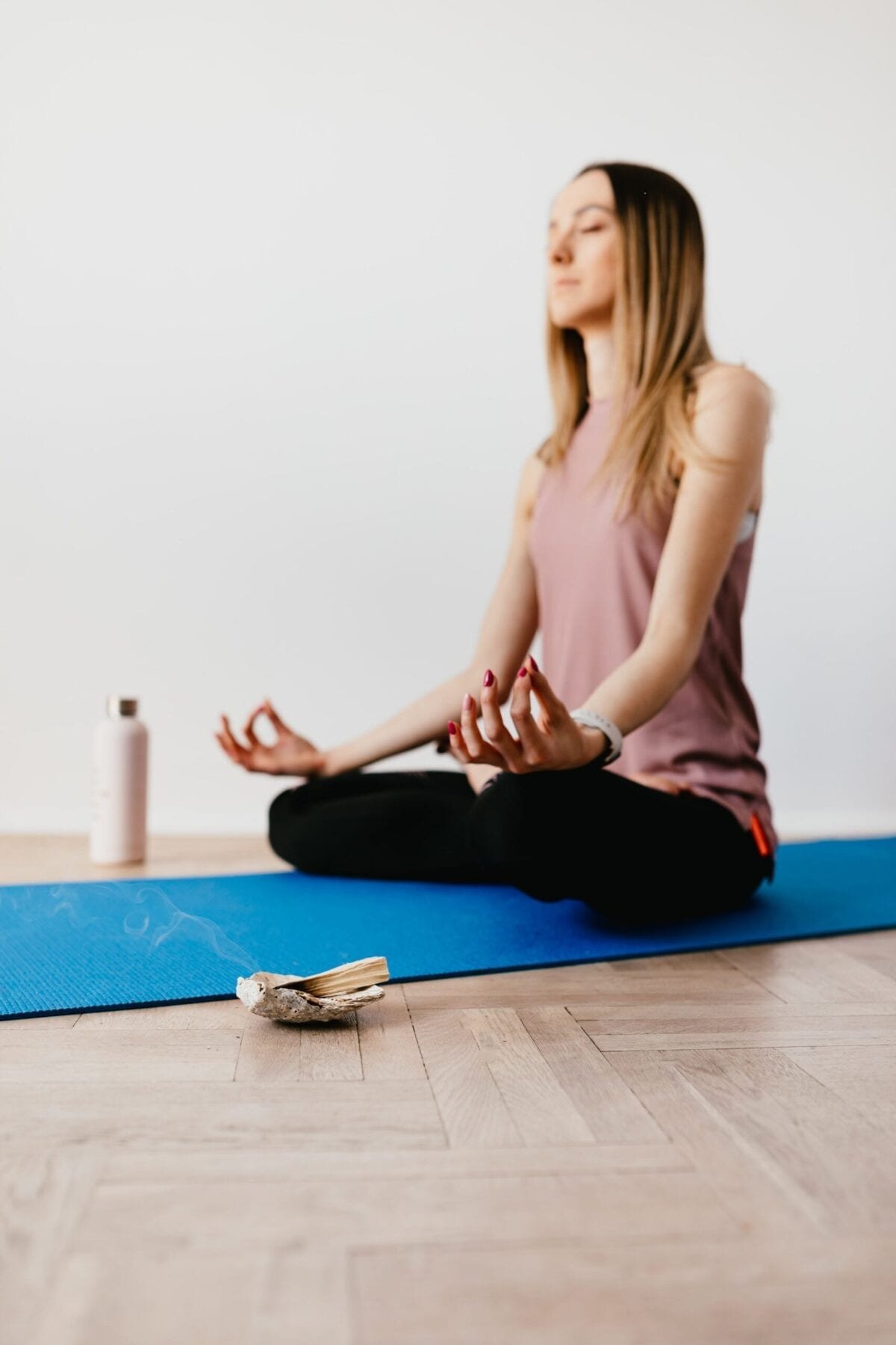 Young woman in Lotus pose with Palo Santo beside