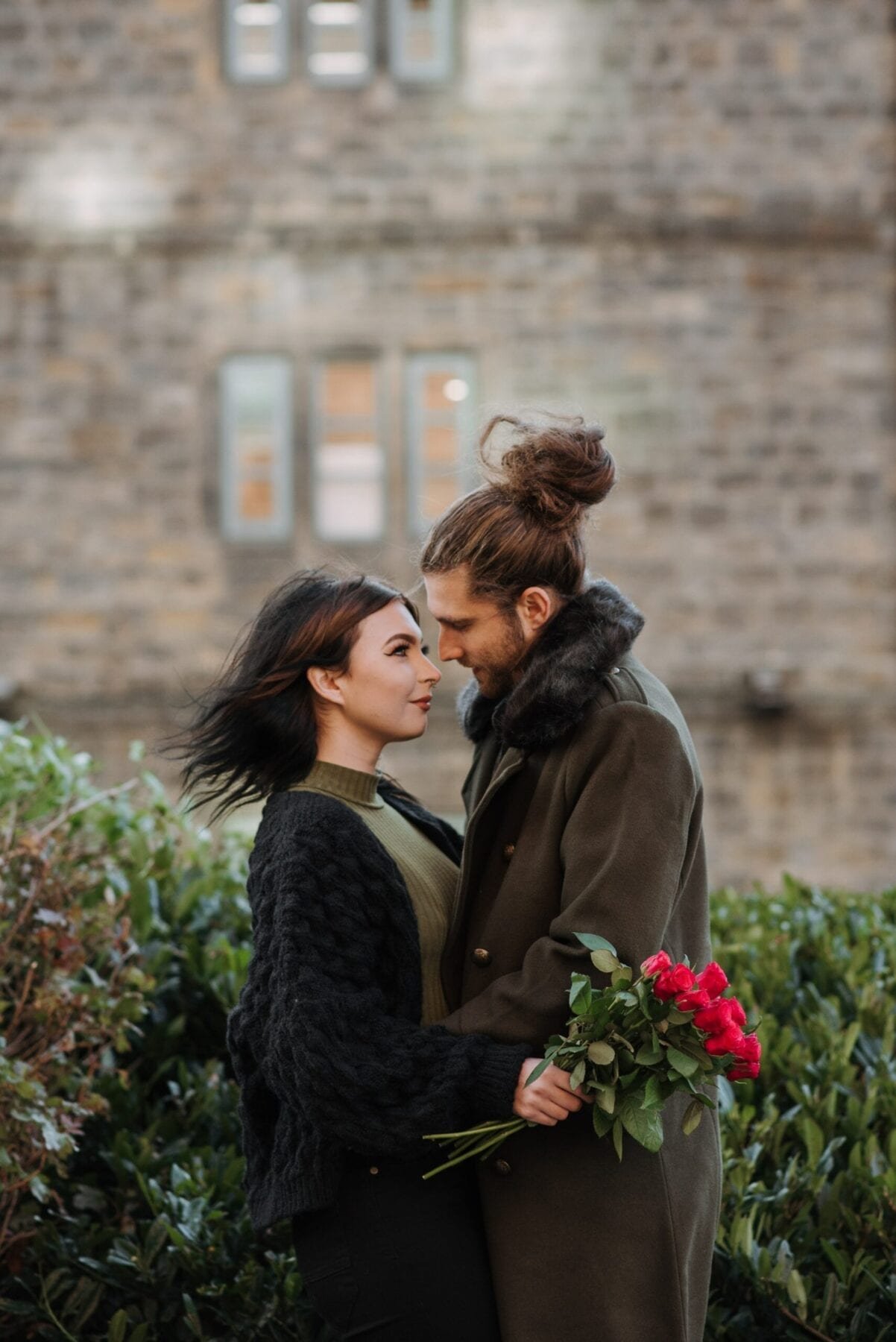 Couple embracing near bushes on city street