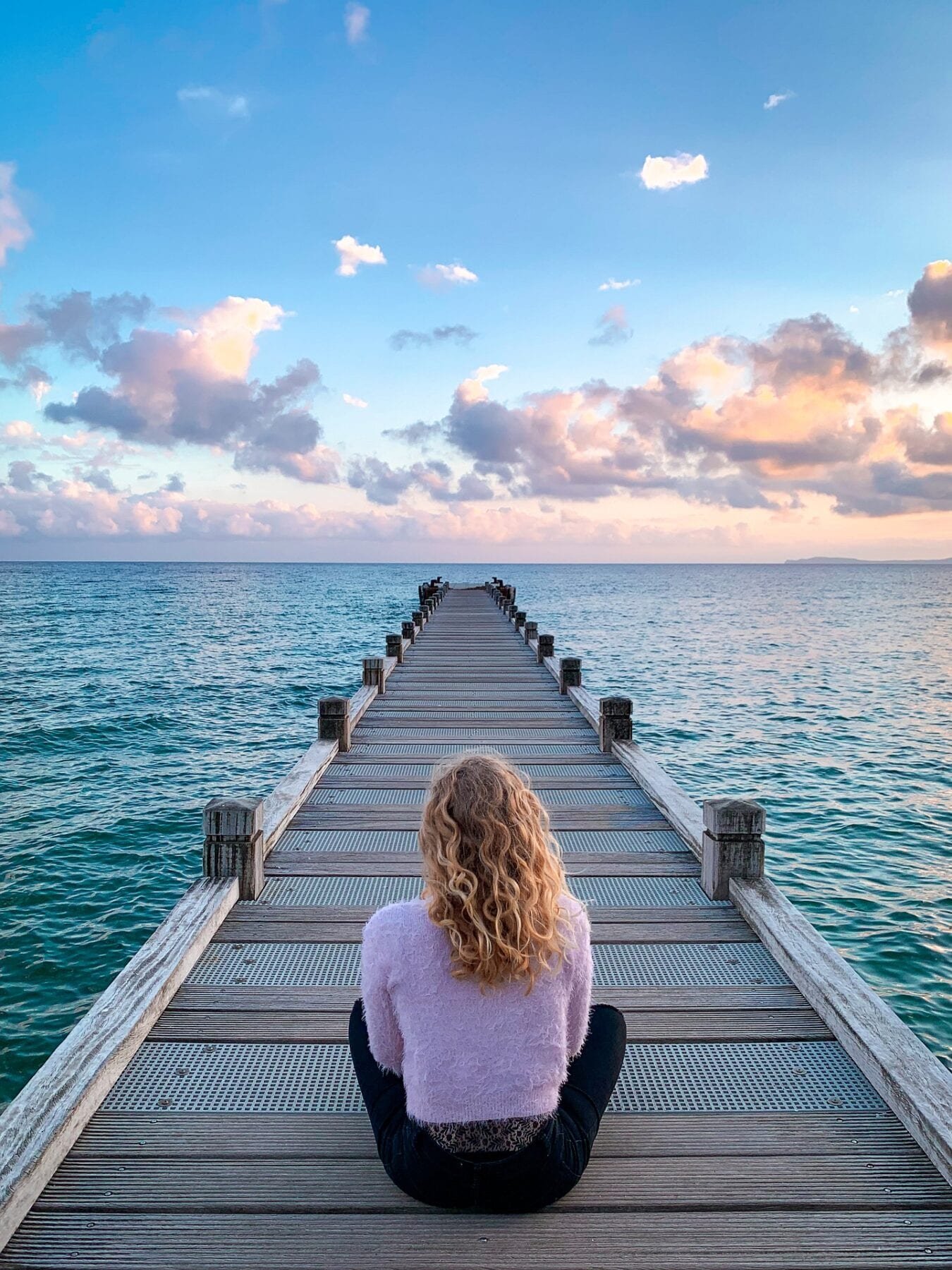 girl sitting on a boardwalk